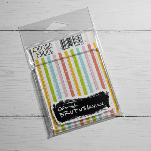 Packaged acrylic block with striped design on a gray surface